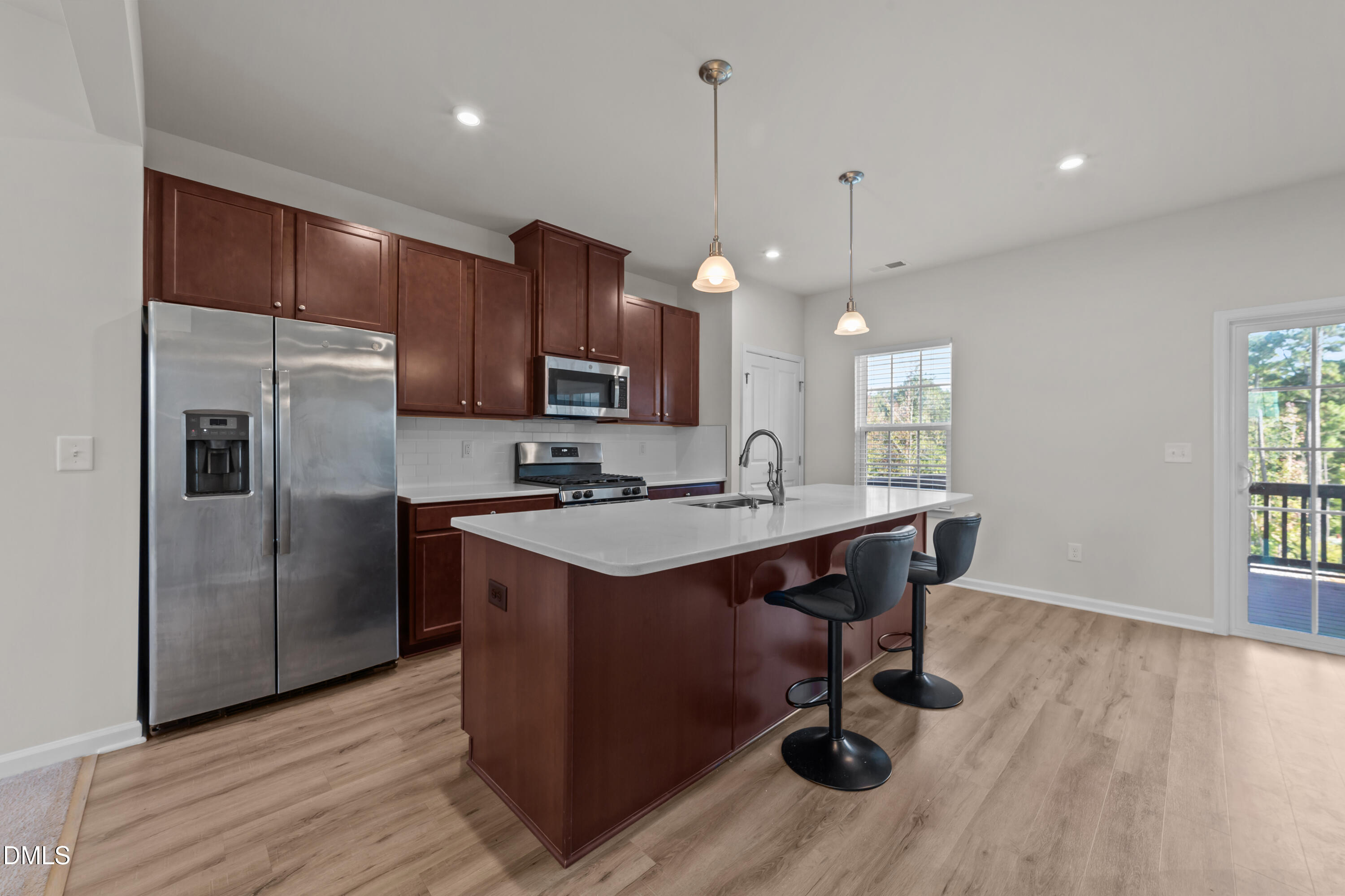 354 Amber Acorn Avenue Raleigh, NC 27603 - Photo 5 of 47 a kitchen with kitchen island a wooden floor and a refrigerator