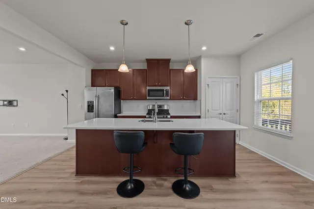 a room with stainless steel appliances kitchen island a large island in the center