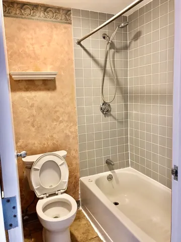 a white toilet sitting next to a bath tub and a shower