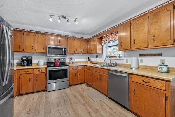 a kitchen with stainless steel appliances granite countertop a sink a stove a refrigerator cabinets and a window