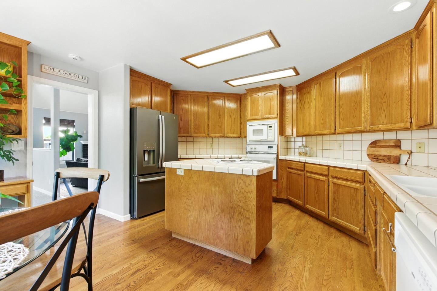 735 Georgetown Place Gilroy, CA 95020 - Photo 10 of 48 a kitchen with stainless steel appliances kitchen island granite countertop a refrigerator a stove top oven and a dining table with wooden floor