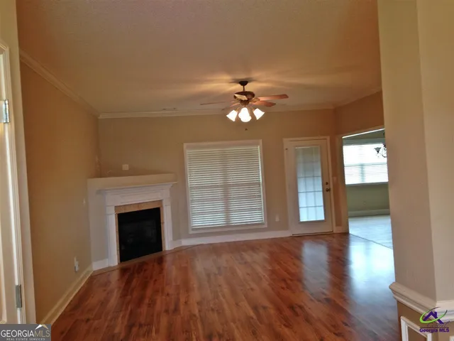 a view of an empty room with wooden floor fireplace and a window