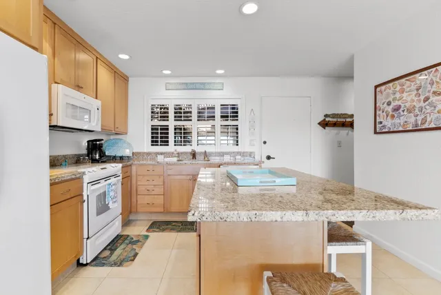 a kitchen with kitchen island granite countertop a stove and a refrigerator