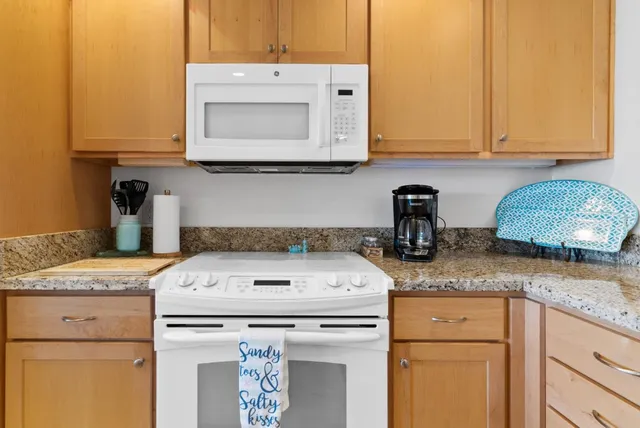 a kitchen with granite countertop a sink a stove and cabinets