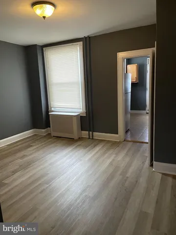 an empty room with wooden floor and window