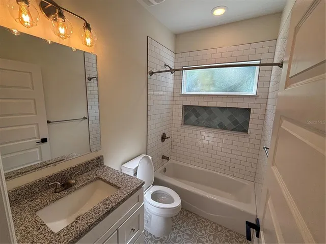 a bathroom with a granite countertop sink toilet and shower