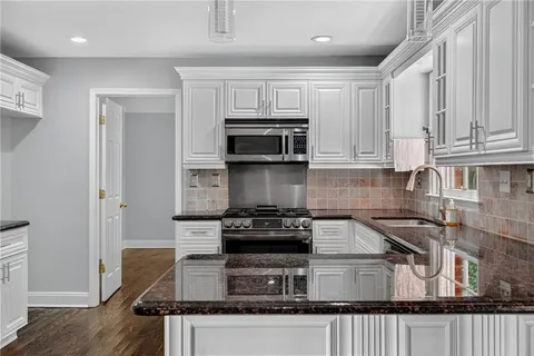 a kitchen with kitchen island granite countertop a stove and a microwave