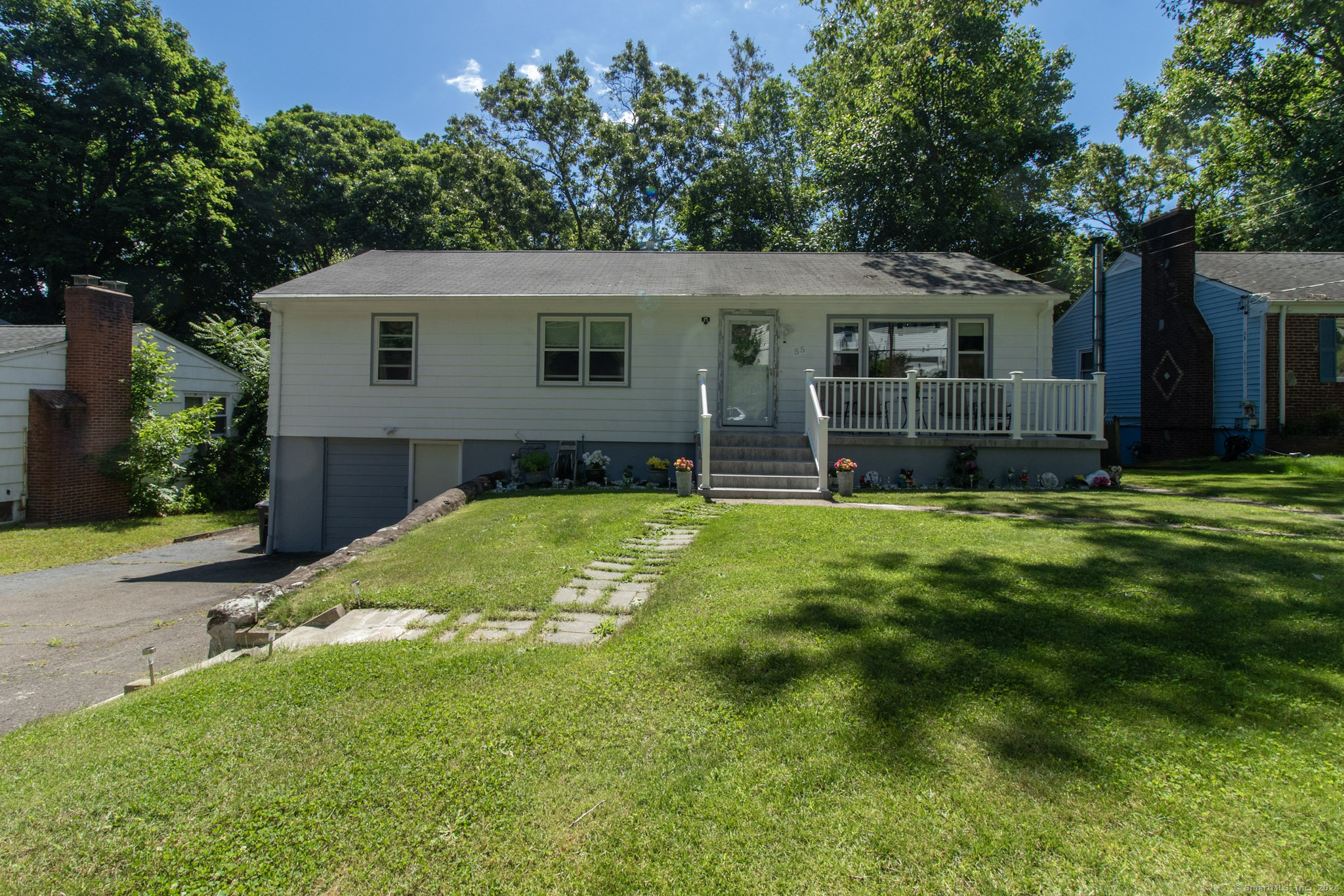 a view of a yard in front of a house with plants and large tree