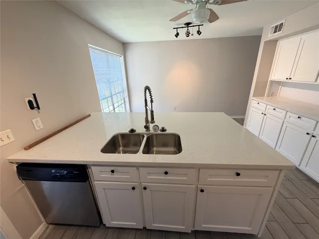 a kitchen with a sink dishwasher and white cabinets