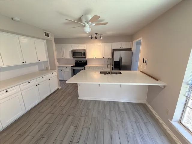 a view of kitchen with sink microwave refrigerator and cabinets