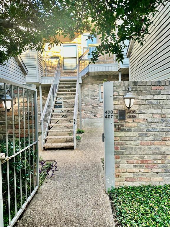 7340 Skillman Street, Unit 405 Dallas, TX 75231 - Photo 15 of 18 Brick and siding exterior featuring a wrought iron gate, concrete walkway, and an external staircase leading to upper units