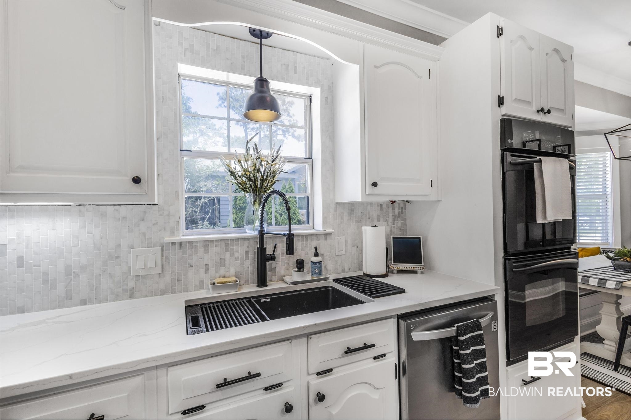 83 Caisson Trace Daphne, AL 36527 - Photo 22 of 63 Modern kitchen featuring white cabinetry with dark hardware, a white countertop, and a mosaic tile backsplash
