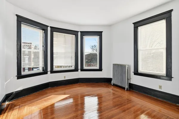 a view of an empty room with a window and wooden floor