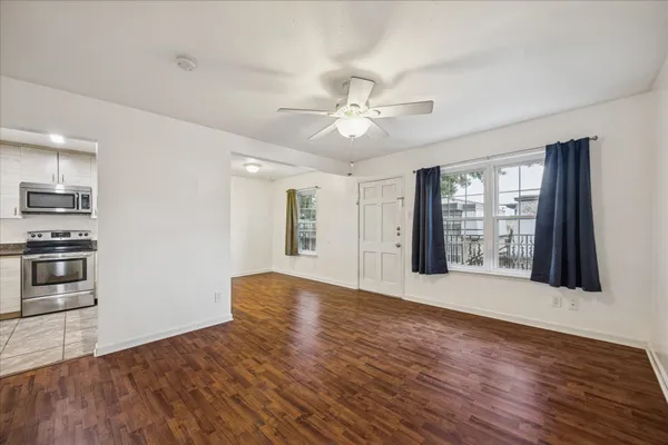 a view of an empty room with a window and wooden floor