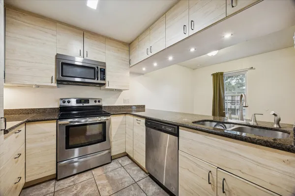 a kitchen with granite countertop a sink a stove and microwave