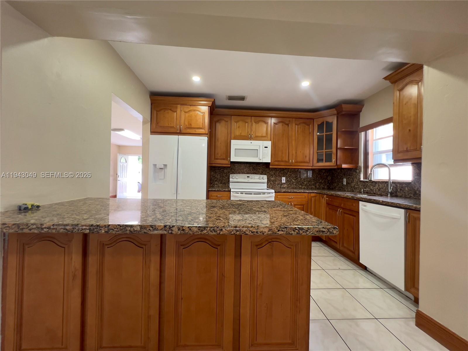 2761 Southwest 33rd Court, Unit A Miami, FL 33133 - Photo 3 of 22 a large kitchen with granite countertop a sink and cabinets