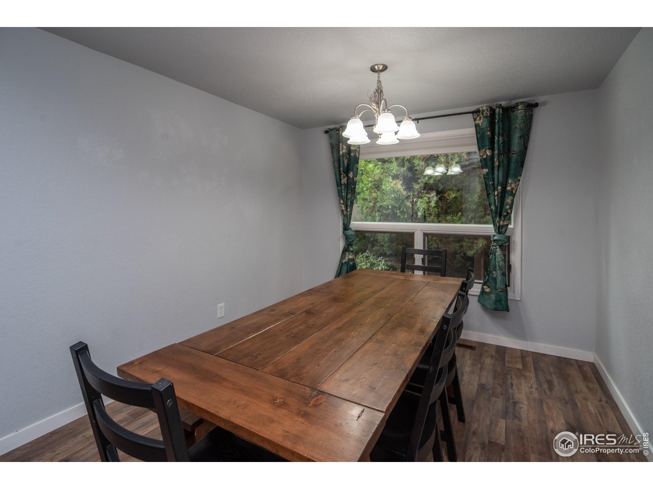 10879 West 65th Way Arvada, CO 80004 - Photo 12 of 39 a dining room with wooden floor a chandelier a wooden table and chairs
