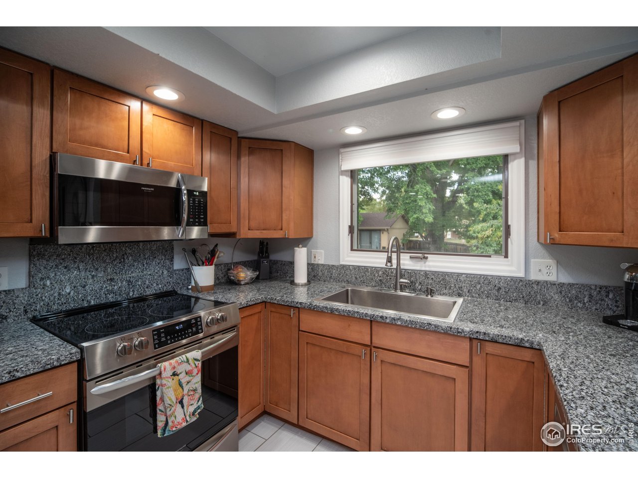 10879 West 65th Way Arvada, CO 80004 - Photo 6 of 39 a kitchen with kitchen island granite countertop a sink stainless steel appliances and cabinets