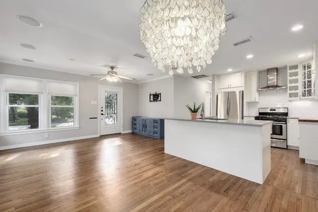 an open kitchen with kitchen island and stainless steel appliances with wooden floor