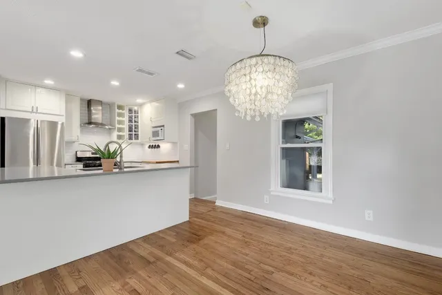 a view of a kitchen with stainless steel appliances wooden floor and chandelier