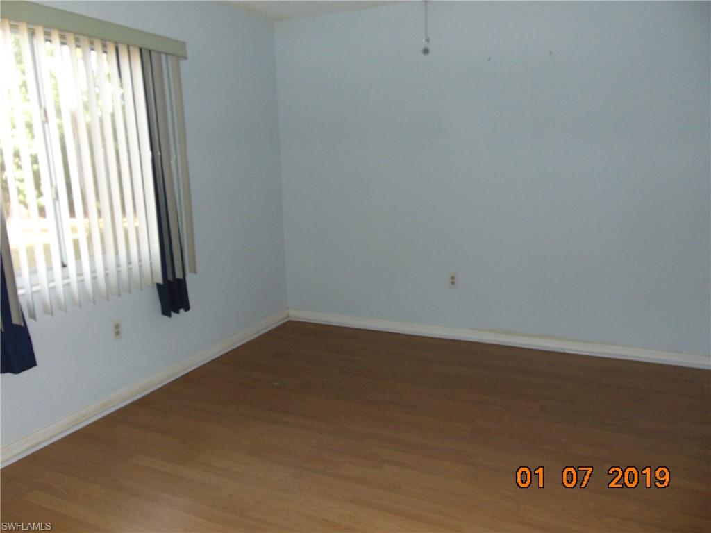 5685 Whitaker Road, Unit C102 Naples, FL 34112 - Photo 6 of 10 an empty room with wooden floor and windows