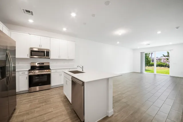 a kitchen with stainless steel appliances a stove a sink a microwave a refrigerator a stove a microwave and cabinets