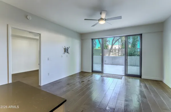 an empty room with wooden floor fan and windows