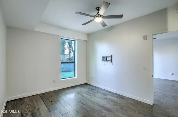 an empty room with wooden floor ceiling fan and windows