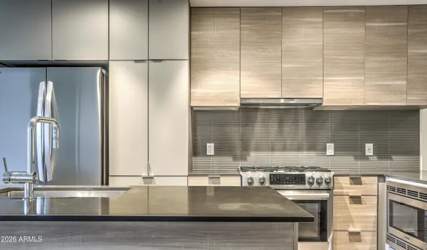 view of kitchen with stainless steel appliances granite countertop a sink and a refrigerator