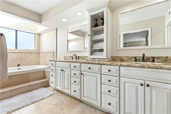 a bathroom with a granite countertop tub sink and mirror