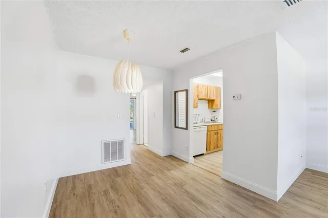 an empty room with wooden floor mirror and window
