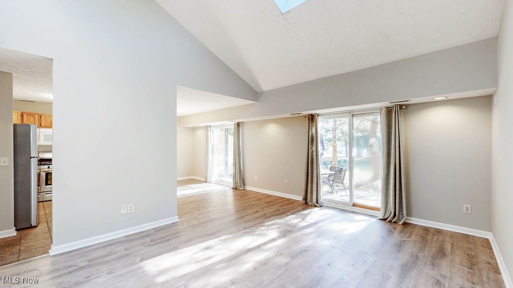 1426 Loop Road, Unit 1426 Kent, OH 44240 - Photo 8 of 40 Living room with high vaulted ceiling, light wood finished floors, and a skylight and sliding doors leading to private patio area.