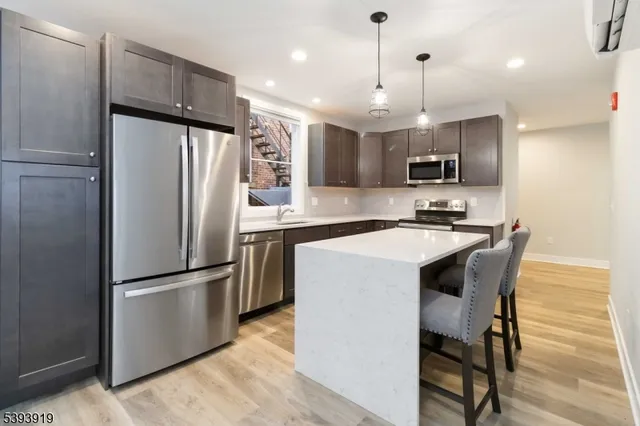a kitchen with kitchen island a refrigerator a counter top space appliances and cabinets