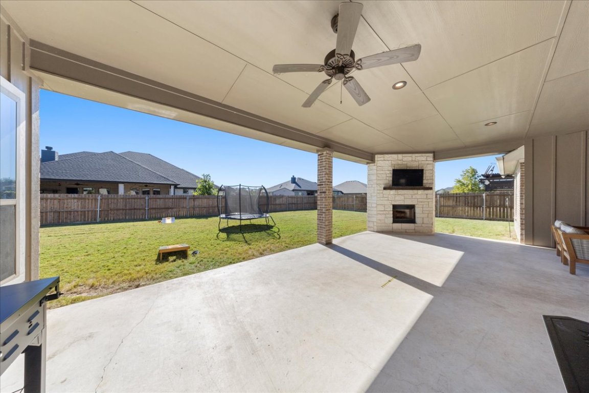 3810 Green Tree Loop Temple, TX 76502 - Photo 34 of 40 Fenced backyard featuring a trampoline, a patio area, an outdoor stone fireplace, and ceiling fan