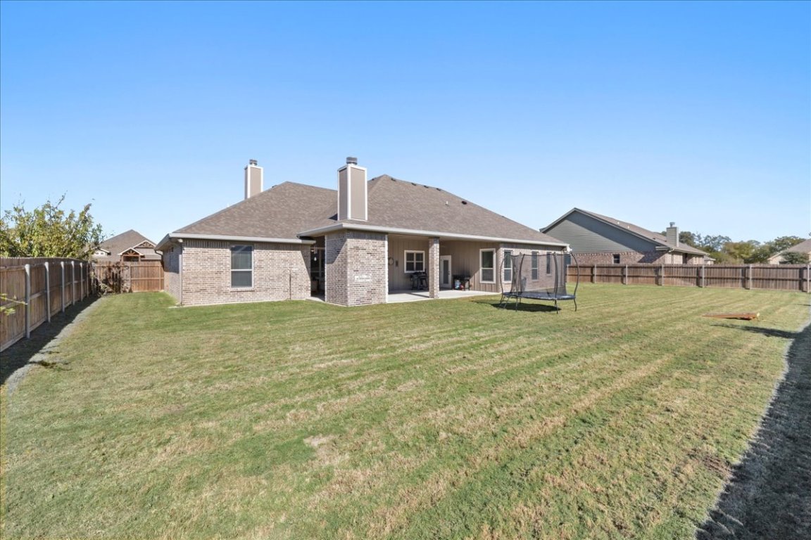 3810 Green Tree Loop Temple, TX 76502 - Photo 37 of 40 Rear view of house with a trampoline, a chimney, a fenced backyard, a patio, and brick siding