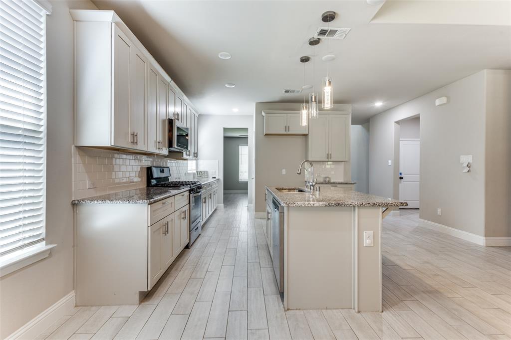 2912 Inn Kitchen Way McKinney, TX 75071 - Photo 3 of 29 a kitchen with stainless steel appliances kitchen island granite countertop a stove a sink and a refrigerator