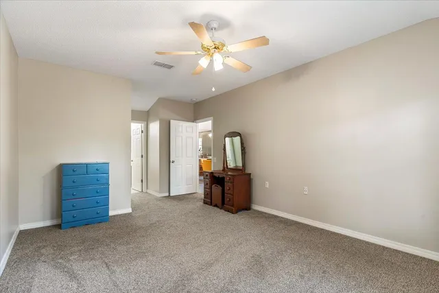 an empty room with chandelier fan and windows