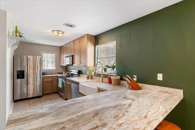 a open kitchen with stainless steel appliances granite countertop a sink dishwasher stove and refrigerator with wooden floor