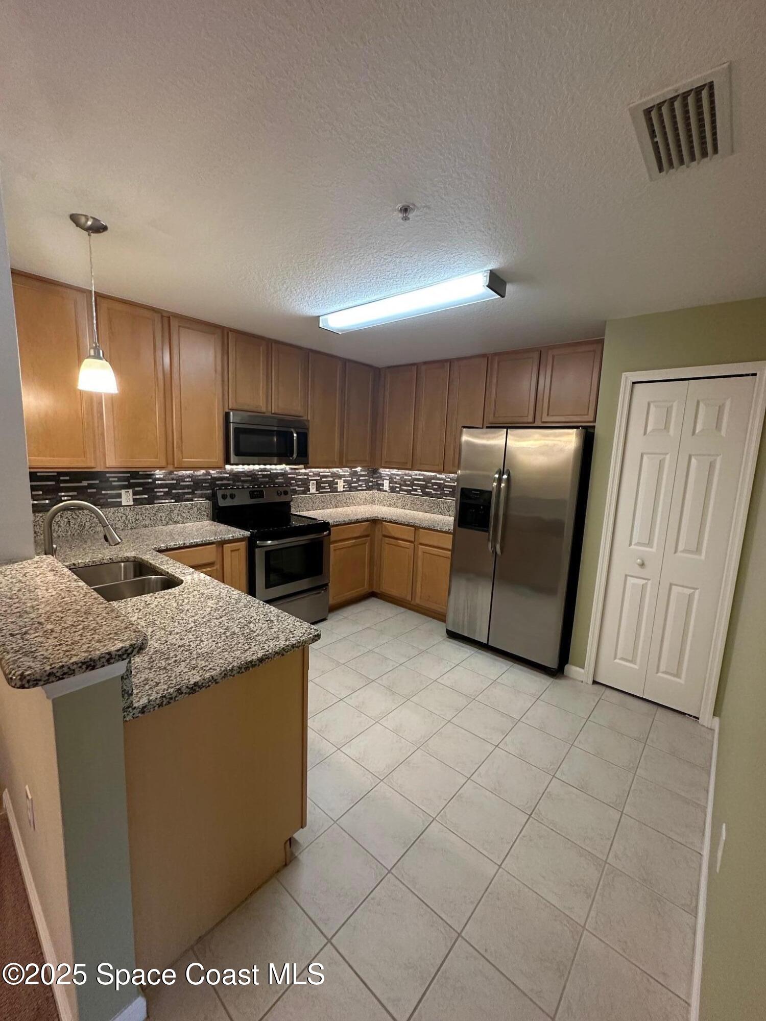 4106 Meander Place, Unit 208 Rockledge, FL 32955 - Photo 4 of 19 a kitchen with stainless steel appliances granite countertop a refrigerator a stove a sink and a microwave
