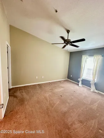 a view of a room with a ceiling fan and window