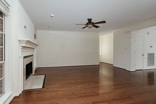 a view of an empty room with wooden floor and a fireplace