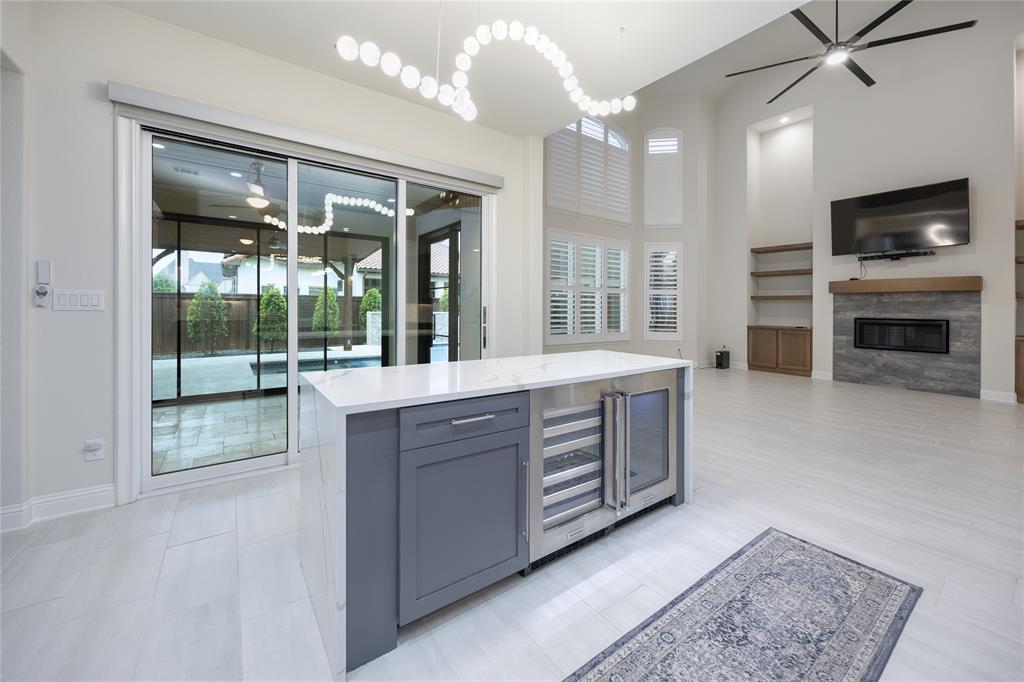 918 Sydney Lane Allen, TX 75013 - Photo 9 of 40 Spacious living area featuring high ceilings, large windows with plantation shutters, a modern fireplace with a tiled surround, and built-in shelving