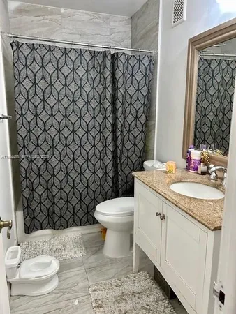 a bathroom with a granite countertop toilet and sink
