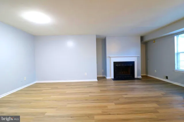 a view of empty room with wooden floor and fireplace