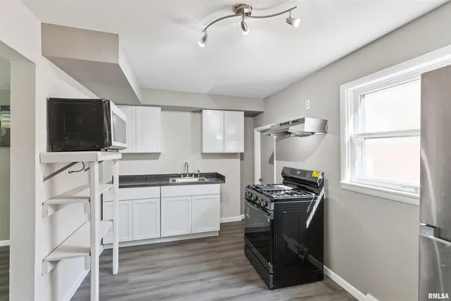 a kitchen with stainless steel appliances kitchen island granite countertop a stove refrigerator and microwave