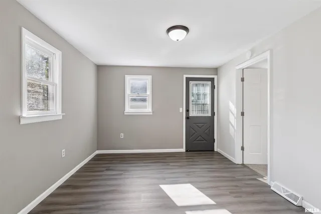 a view of an empty room with wooden floor and closet