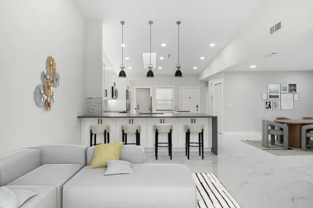 a living room with furniture a table and kitchen view