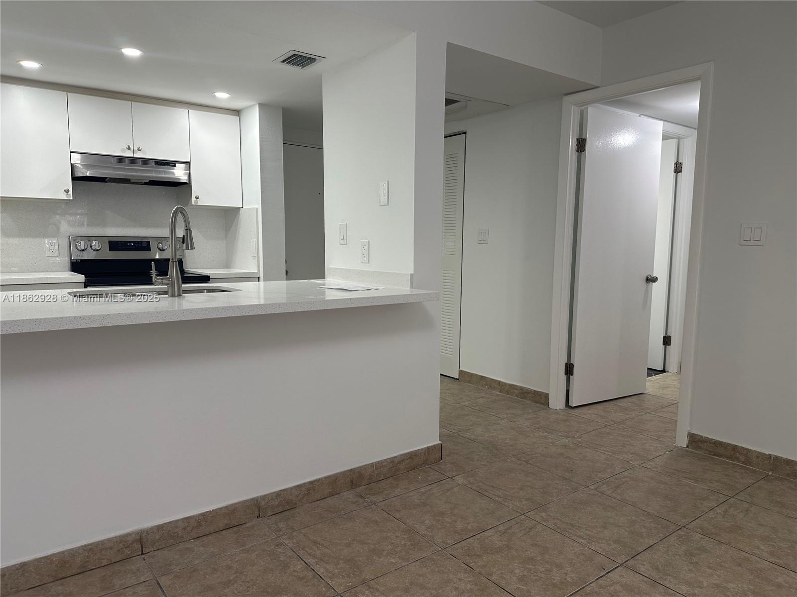 8100 Geneva Court, Unit 142 Doral, FL 33166 - Photo 1 of 11 a kitchen with kitchen island a sink stainless steel appliances and cabinets