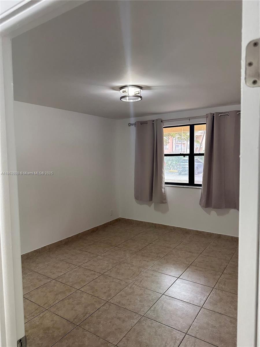 8100 Geneva Court, Unit 142 Doral, FL 33166 - Photo 11 of 11 an empty room with chandelier fan and windows