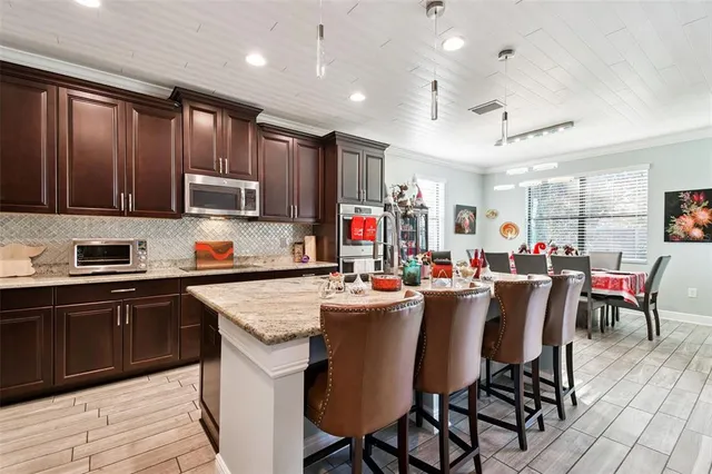 a kitchen with stainless steel appliances granite countertop a stove top oven a sink dishwasher a dining table and chairs with wooden floor